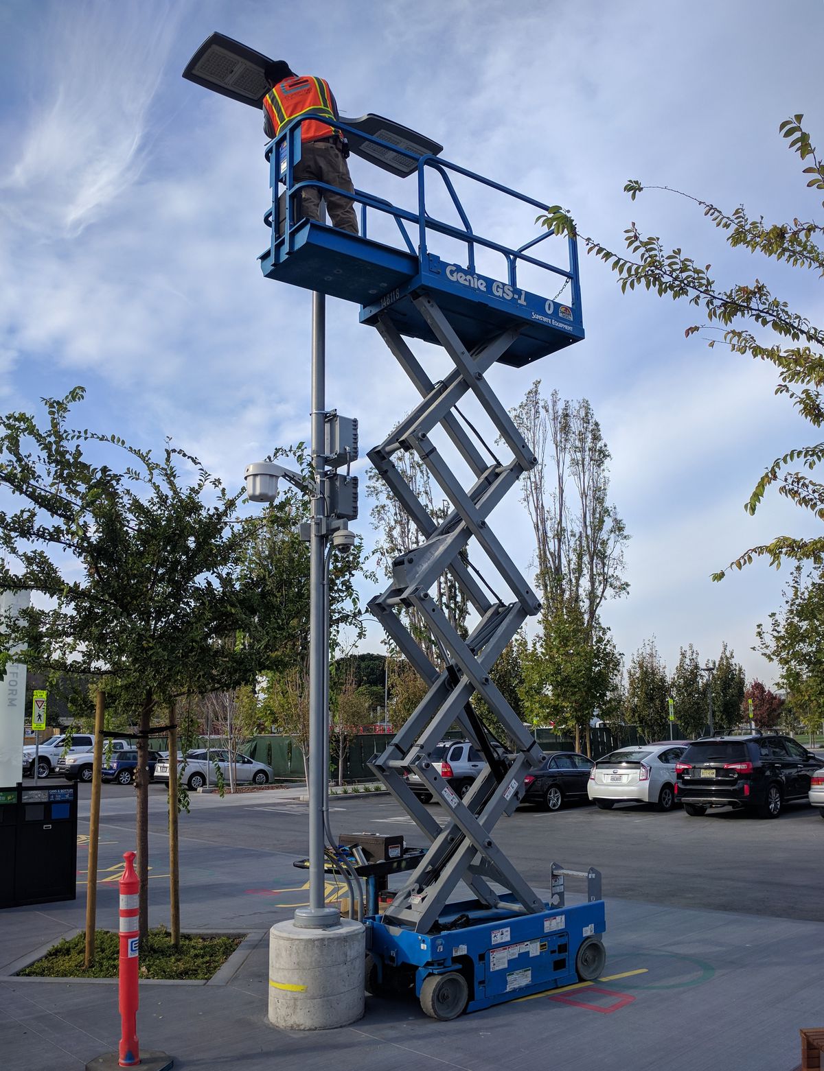 Electrician servicing an overhead light fixture from a lift